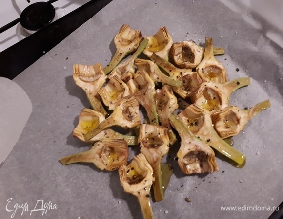 Выложите очищенные артишоки на бумагу для запекания, полейте оливковым маслом, добавьте крупную соль и черный перец. Сверните бумагу в конверт и поставьте в духовку на 35 минут.