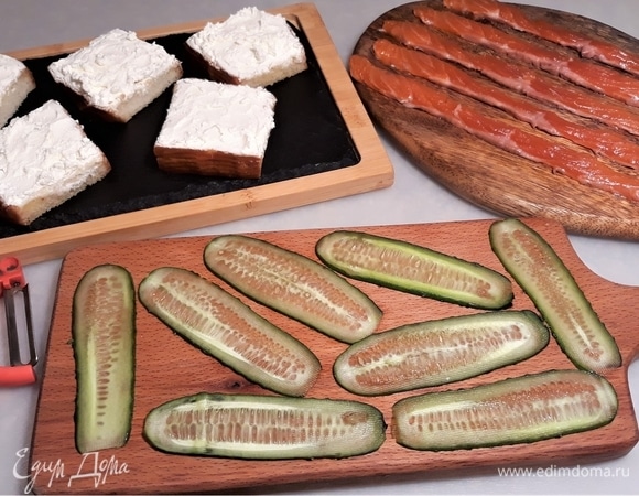 Огурцы очень тонко нарежьте вдоль на полоски — это удобно делать овощечисткой. Выложите на поджаренный хлеб сливочный творожный сыр.