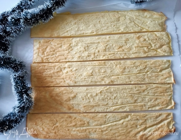 Тем временем с бисквита снять бумагу и разрезать его на пять полосок примерно по 6–6,5 см.