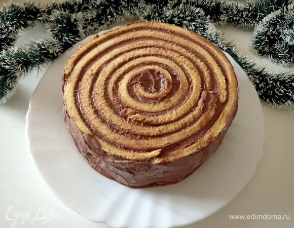 Свернуть первую полоску бисквита в рулет. Поставить на блюдо. К концу полоски приложить следующую и продолжить заворачивать рулет до тех пор, пока не закончится весь бисквит. Промазать бока тортика оставшимся кремом.