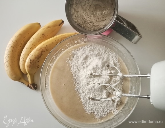 Уменьшить скорость миксера до минимума и добавить банановое пюре, затем — просеянную муку, разрыхлитель и соду.
