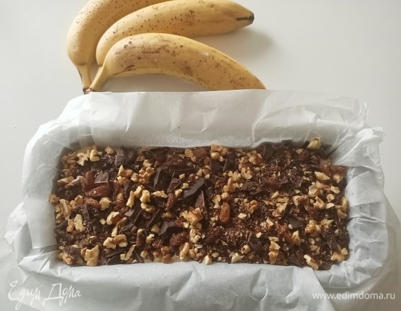 Форму для кексов застелить пергаментной бумагой. Выложить тесто. Сверху посыпать второй частью сухофруктов с шоколадом.