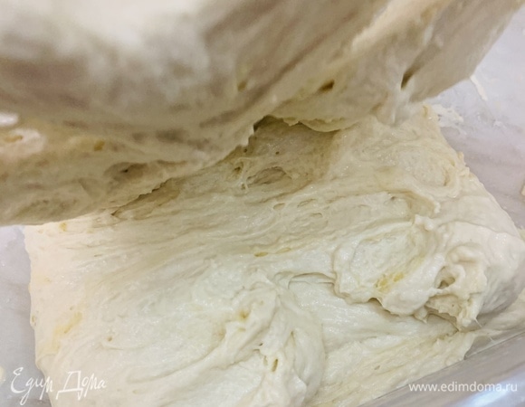 Через 45 минут тесто по-прежнему будет неплотным. Промакиваем руки в воде и мокрыми руками складываем тесто, вытягивая его внахлест — с одного края на другой, как конверт. Делаем так со всех четырех сторон. При первом складывании тесто может немного рваться, но это только вначале. Дальше клейковина выработается, и тесто станет гораздо эластичнее. Каждый раз смачиваем руки водой, чтобы тесто не прилипало к рукам. Как только сложили тесто со всех четырех сторон, снова накрываем его крышкой и оставляем отдыхать еще на 45 минут.