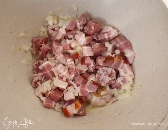Нарежьте грудинку и колбаски на крупные кусочки и обжарьте вместе с луком.