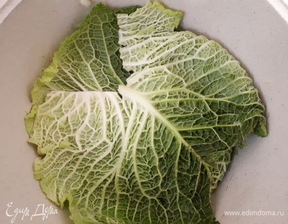 Возьмите пару листов капусты. У меня на фото савойская, так как у нее листья больше и проще отделяются от кочана, но можно использовать и обычную капусту. Срежьте черенок у основания, чтобы проще было расправить листья, и накройте ими лук и копчености. Пульмай готовится слоями, которые отделяют капустными листьями.