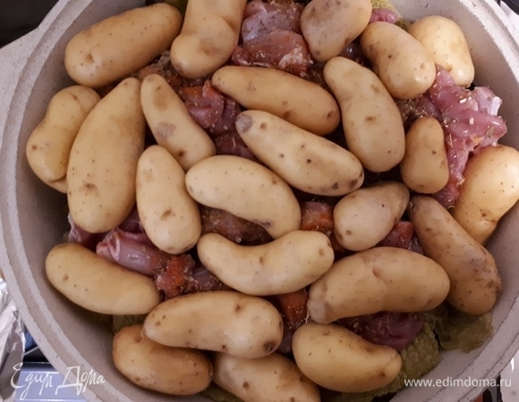 Откройте кастрюлю, снимите фольгу, но не выкидывайте. Выложите курицу сверху на капустные листья и посыпьте приправами. Выложите картофель. Лучше брать картофель помельче. Накройте сверху капустными листьями и опять закройте кастрюлю фольгой и крышкой. Оставьте на 20 минут.