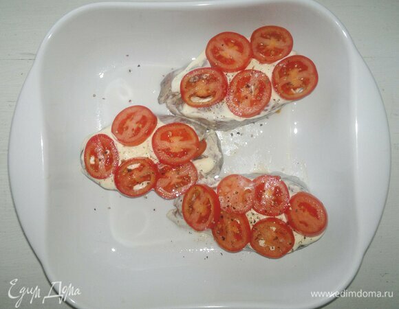 Выложить на стейки оставшуюся сметану, разложить кружки помидоров, немного поперчить.