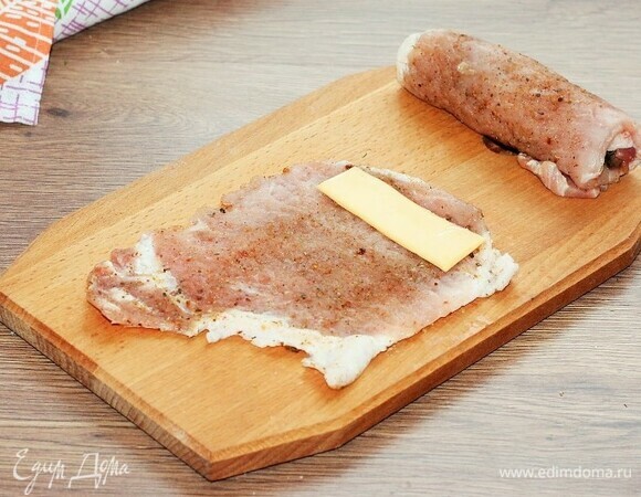 На край отбивной кладем пластину сыра (1/3 часть).
