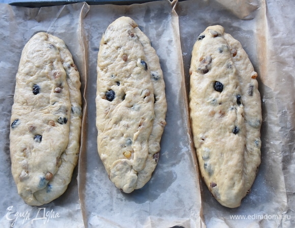 Приступаем к формовке штолленов. Делим готовое тесто на части. Можно приготовить два больших или три средних штоллена. Каждую часть раскатываем в овальной формы лепешку. Складываем лепешку пополам, накрывая 2/3 части. Заготовки кладем на противень, застеленный пергаментом, и оставляем их на расстойку минут на 40. За это время заготовки должны увеличиться в объеме. В разогретую до 180°C духовку помещаем противень с изделиями и выпекаем их до готовности минут 40–45. Готовые штоллены достаем из духовки, даем отдохнуть 2–3 минуты, смазываем растопленным сливочным маслом и очень щедро посыпаем густым слоем сахарной пудры. Теперь готовые штоллены должны созреть. Для этого остывшую выпечку заворачиваем в пергамент, а сверху оборачиваем пищевой фольгой. В прохладном месте хранятся штоллены до 1 месяца.