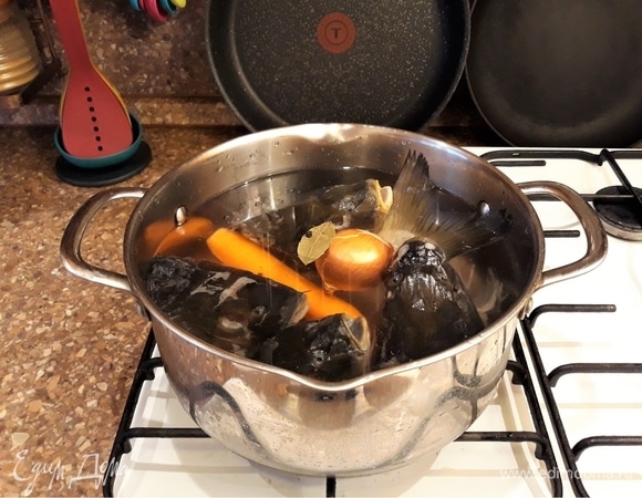 Приготовим бульон для заливного из суповых частей рыбы. У меня в морозилке всегда присутствуют рыбные головы, так как очень любим карпа. Рыбу готовлю в духовке, а головы складываю в морозильную камеру для супа или заливного. Головы разморозить, морковь почистить. Сложить все ингредиенты для бульона в кастрюльку, отварить до готовности.