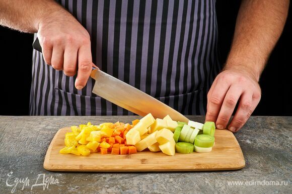 Картофель и морковь почистите и нарежьте кубиками. Лук-порей нарежьте кольцами. Болгарский перец нарежьте средним кубиком.
