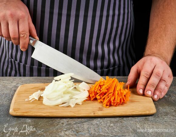 Нарежьте лук полукольцами, а морковь — тонкими брусочками.