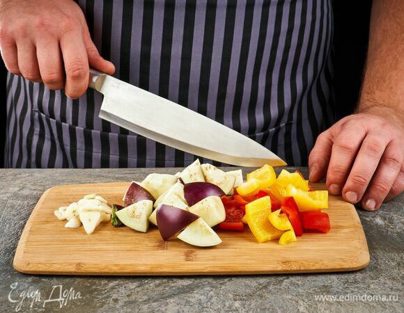 Перец очистите от перегородок и семян, нарежьте кубиком, баклажан нарежьте крупными кубиками, чеснок мелко порубите.