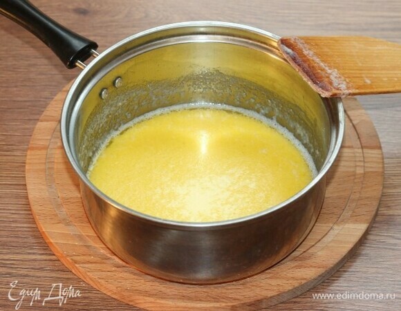 Добавьте в масляную смесь 100 мл молока. Поставьте сотейник на медленный огонь и, перемешивая, добавьте оставшееся молоко.