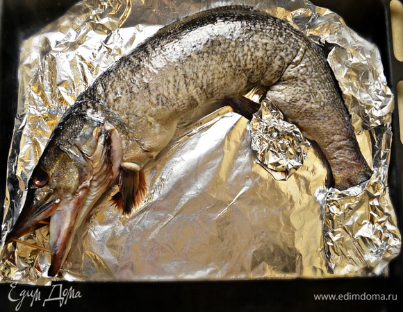 Голову скрепляем с тушкой с помощью ниток или зубочисток. На противень укладываем фольгу, смазываем ее растительным маслом. Выкладываем щуку и смазываем растительном маслом всю поверхность. Чтобы хвост не обгорел во время запекания, я его предусмотрительно завернула в фольгу. В пасть щуки вставляем зубочистки, чтобы зафиксировать ее открытой.