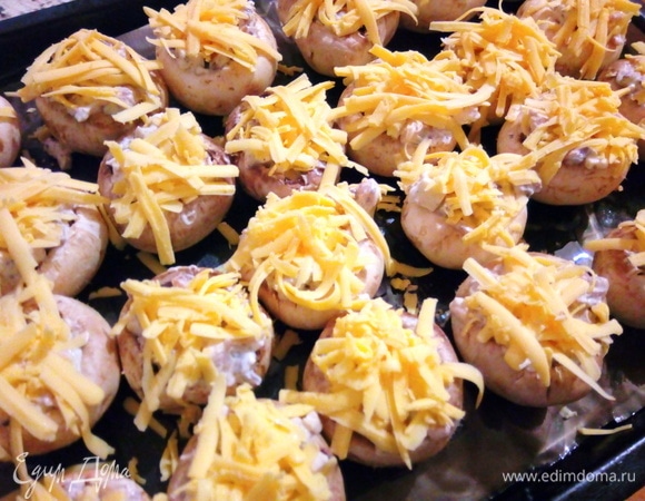 Твердый сыр натираем на крупной терке и посыпаем им сверху фаршированные шампиньоны. Отправляем в духовку при 190°C на 15–20 минут. Ориентируйтесь на свою духовку.