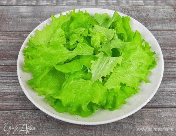 Салатные листья помыть, обсушить, порвать на средние кусочки и выложить на блюдо.