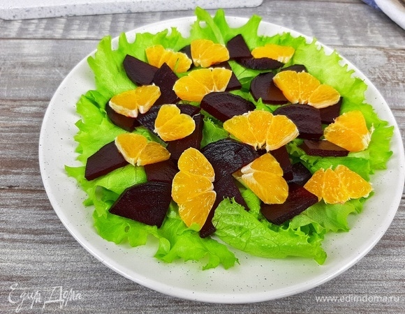 Выкладываем на салатные листья свеклу, мандарины, кусочки феты и посыпаем орехами. Я еще украсила руколой.