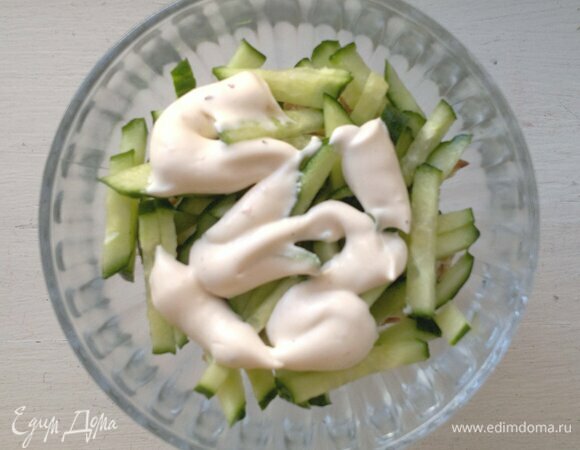 Выложить половину нарезанных огурцов. Смазать их частью майонеза.