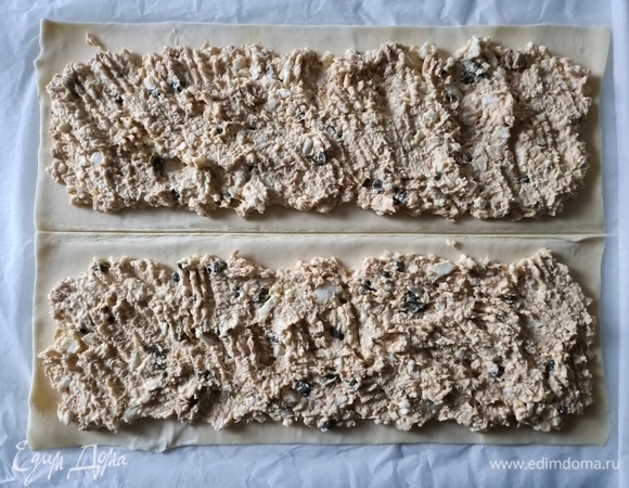 Развернуть прямоугольное слоеное тесто, немного раскатать. Разделить его на две части. Сверху выложить начинку.