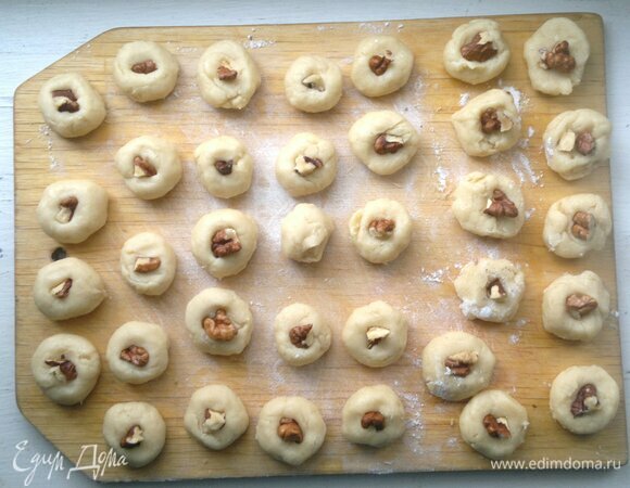 От теста отрывать маленькие кусочки теста. В середину каждого кусочка теста вставить кусочек ореха.