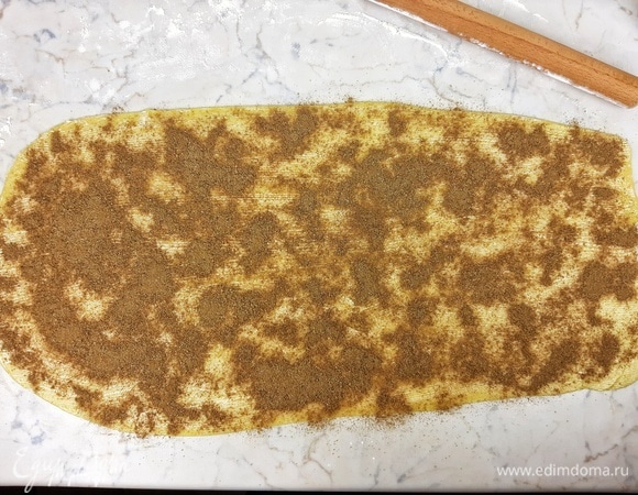 Раскатываем тесто в прямоугольник размером 60 х 30 см. Смазываем сливочным маслом комнатной (!) температуры. Посыпаем равномерно сахаром с корицей и 3/4 орехов. Скручиваем в тугой рулет по длинной стороне.