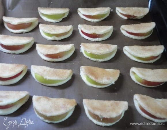 Погрузить печенье смазанной поверхностью в сахар с корицей. Выложить на противень, застеленный пергаментом. Выпекать 20–25 минут. Поверхность печенья должна хорошо подрумяниться, а яблоки — пропечься.