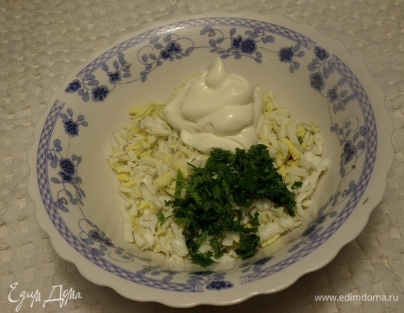 В чашку выкладываем натертое яйцо. Добавляем майонез и нарезанную зелень. Аккуратно перемешиваем.