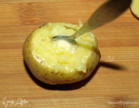 Достать картофель из духовки, дать немного остыть. С теплого картофеля срезать верхушки. Добавляем сливочное масло. Чайной ложкой толчем середину картофеля с маслом до однородной массы. Сверху добавляем чайную ложку икры. Закуска готова.