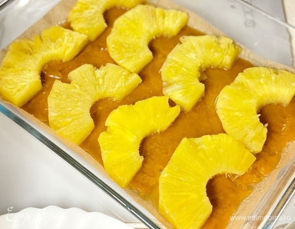 Дно формы выстелить пергаментом, вылить карамель и выложить ломтики ананаса.