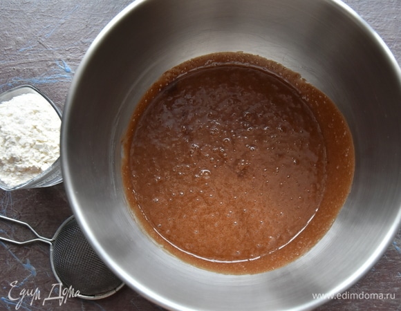 Муку просеять через сито, добавить в жидкую составляющую и аккуратно вмешать ее, воспользовавшись силиконовой лопаткой, движениями снизу вверх.