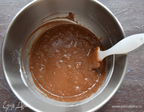 Форму выстелить пергаментом и смазать небольшим количеством масла. Выложить шоколадное тесто, равномерно распределить его и слегка постучать формой о поверхность, чтобы избавить тесто от воздушных пустот.