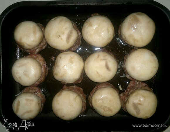 Вставить в углубления грибы, немного вдавливая их в фарш. Смазать шляпки оставшимся растительным маслом. Поставить форму в духовку, разогретую до 180°C, на 20–25 минут.