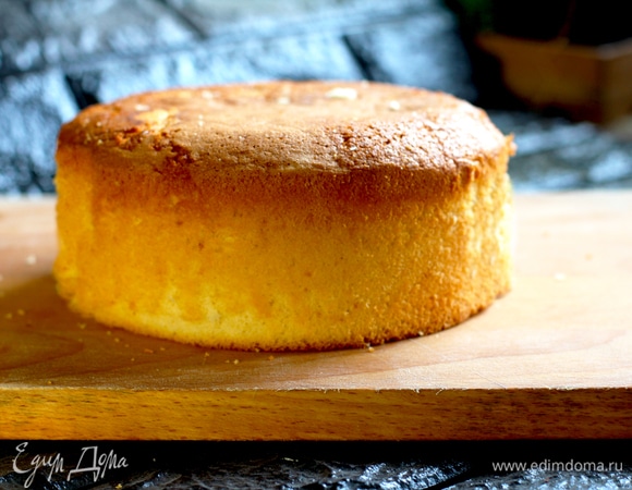 Для этого торта я выбрала бисквит на горячем молоке, можно брать любой ванильный. Выход бисквита — около 520 г. Так как на все приготовление уходит минут 10–15, то заранее приготовим духовой шкаф и формочку. Разогреваем духовку до 170°C, режим «верх-низ», без конвекции. Подготовим форму для выпечки. Я выпекаю в кольце 18 см, обернув его фольгой. Лично я ничем не смазываю бортики, но вы можете предварительно бока формы смазать маслом и посыпать мукой. На дно формы укладываем пергамент. Далее переходим, собственно, к приготовлению самого вкусного бисквита на горячем молоке и сливочном масле. Яйца помещаем в дежу миксера и начинаем взбивать со щепоткой соли. Яйца должны быть комнатной температуры, так они лучше взобьются. Как только на поверхности появится хорошая пенка, начинаем постепенно всыпать наш сахарный песок и ванильный сахар, не прекращая взбивать. Взбиваем яичную смесь минут 5–7 (в зависимости от мощности вашего миксера). Масса должна очень хорошо увеличиться в объеме и немного держать форму. Пока взбиваются яйца, надо просеять муку с разрыхлителем и перемешать их. В сотейник наливаем наше молоко и помещаем туда сливочное масло, нарезанное на кубики. Ставим на плиту на средний огонь. Ждем, пока масло полностью разойдется. Кипятить не надо, как только смесь стала однородная, убираем с огня. В яичную массу вмешиваем мучную смесь силиконовой лопаткой аккуратными движениями снизу вверх. Нам надо максимально сохранить всю воздушность взбитых яиц. Муку лучше вмешивать в 2–3 захода, а не всю сразу. Как только масса стала однородной, без комочков, вливаем туда горячее молоко. Перемешиваем максимально аккуратно. Выливаем наше тесто в подготовленную форму и отправляем в разогретую духовку. Выпекаем при 170°C 35–40 минут. Готовность бисквита, как всегда, определяем при помощи деревянной шпажки: выходит сухой — вынимаем. Первые 30 минут духовку лучше не открывать. Готовый бисквит должен пружинить при надавливании. Сначала остужаем наш бисквит в форме минут 15. Далее проходим ножиком по краю, освобождая его от формы. Оборачиваем его в пленку и убираем в холодильник на 8–10 часов на дозревание. Высота готового бисквита у меня, если без горочки, — 7 см. Горку перед сборкой срезаем.