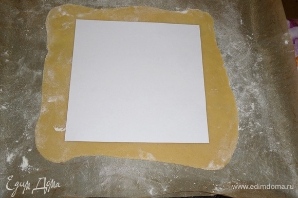 Медовую лепешку выкладываем на коврик для выпечки. Используя бумажный шаблон, обрезаем края.