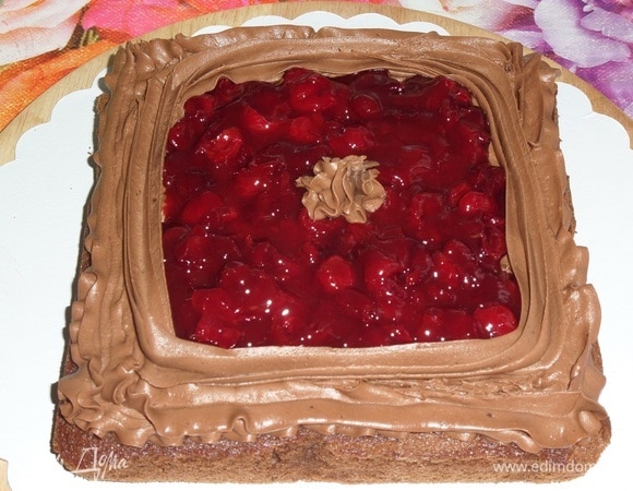 В центральную часть коржа, поверх крема, выкладываем половину вишневой начинки. Равномерно ее распределяем. Делаем кремовые бортики и отсаживаем звездочку крема в центр.