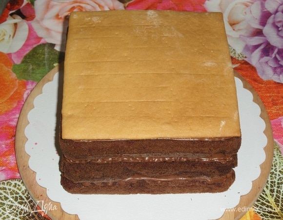 Поверх шоколадного крема укладываем медовый корж. Оборачиваем торт пленкой и кладем сверху небольшой груз, у меня это разделочная доска весом 400 г. Оставляем торт на 4–6 часов в холодильнике.