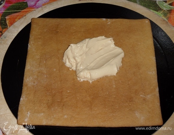 Собираем медовый торт — крышу избушки. Подложку для торта протираем спиртовой салфеткой. В центр подложки кладем 1 ч. л. карамельного крема и укладываем медовый корж.