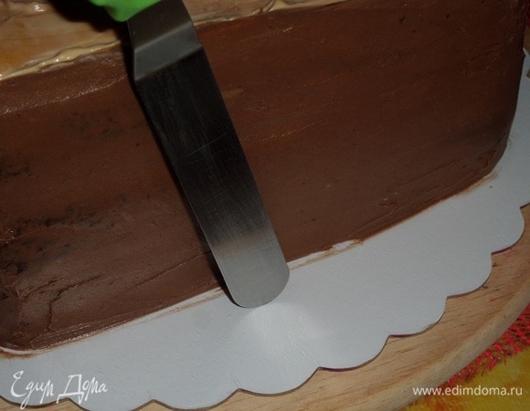 Выравниваем бока торта, используя кондитерский шпатель. Наносим крем на медовый корж и равномерно распределяем.