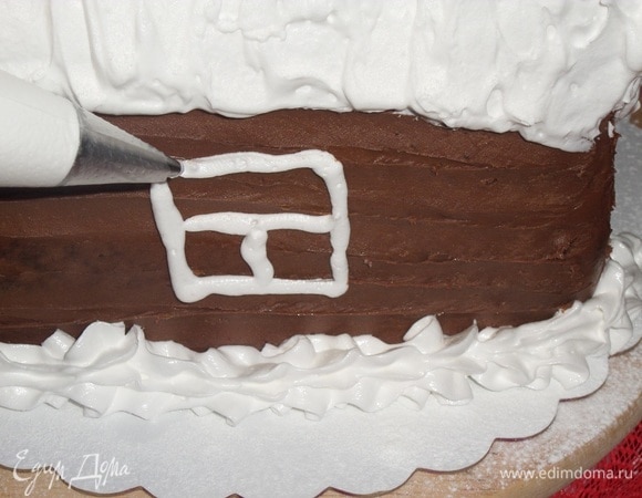 Немного белкового крема откладываем в кондитерский мешок и декорируем избушку: рисуем окна, двери.