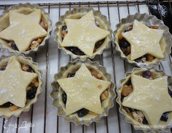 Включите духовку на разогрев до 190°C. Смажьте маслом небольшие формочки для кексов. Раскатайте тесто до толщины 3 мм, вырежьте кружочки и поместите их в формочки, формируя бортик. Наполните начинкой. Оставшееся тесто раскатайте и вырежьте звездочки. Выложите их поверх начинки. Слегка взбейте яйцо и смажьте звезды, слегка посыпьте сахарной пудрой.