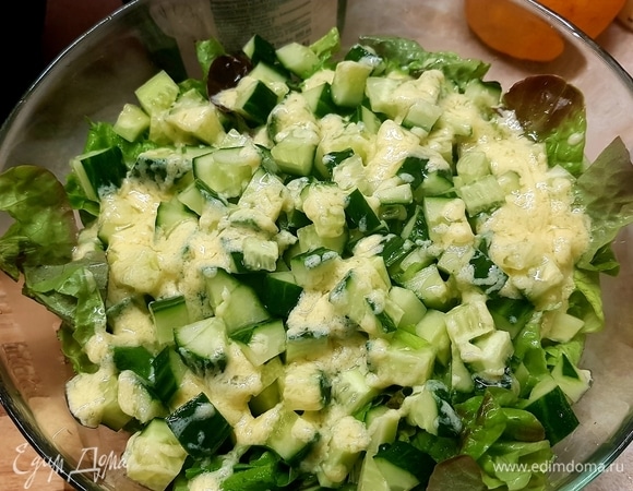 На дно салатника выложить салатный микс. Огурец нарезать кубиком и выложить поверх салата. Полить немного заправкой.