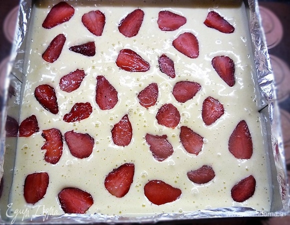 В чаше миксера соединяем яйца с сахаром и взбиваем до плотной пышной пены. Добавляем просеянную муку, аккуратно перемешиваем. Распределяем бисквит в квадратной рамке (26 х 26 см),выкладываем сверху нарезанную небольшими кубиками клубнику и выпекаем примерно 12–14 минут при 170°C.