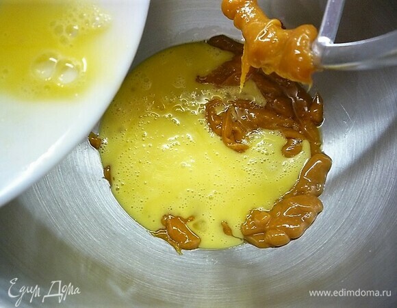 Приготовим карамельные медовые бисквиты. Для этого в сотейник насыпаем сахар и растапливаем до карамельного цвета, не мешаем. В другой кастрюле растапливаем масло и мед, доводим до кипения и выливаем в карамель. Хорошо перемешиваем, остужаем до 70°C. Добавляем в карамельную смесь яйца и соду, насыпаем муку и замешиваем однородное тесто.