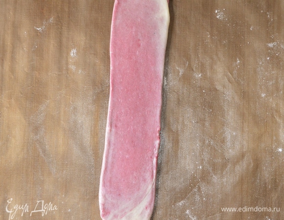 И начинаем раскатывать в длинную полоску. Начинаем катать с середины рулета. Сначала в одну сторону, потом в другую, затем по всей поверхности. Работаем скалкой аккуратно, чтобы не порвались слои. В итоге получаем длинную полосу шириной примерно 4 см и толщиной 2–3 мм.