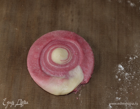 Режем и все остальные рулеты пополам, пока они еще холодные. Разрезанные части держим под пленкой. У нас получится 22 штуки маленьких рулетиков. Теперь надо расплющить маленькие рулеты. Ставим их вертикально на срез или внешнюю витую часть и расплющиваем ладонью. Когда мы будем оборачивать этой лепешкой начинку, эта сторона будет лицевой, то есть верх печенья.