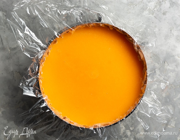 Достать форму с чизкейком из морозилки (или холодильника), снять пленку, поверх залить мандариновым пюре. Накрыть пленкой и убрать в холодильник на 6–8 часов, до полного застывания (лучше — на ночь).