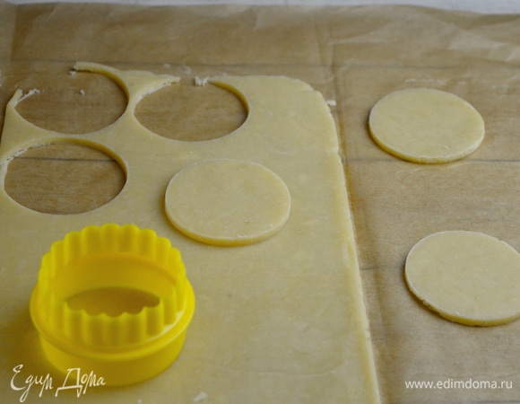 Выкладываем тесто между двух листов пергамента и раскатываем до толщины 2 мм. Убираем в морозилку примерно на полчаса, до получения плотной текстуры. При помощи кулинарного кольца размером 5,5 см вырезаем из теста круглые заготовки и раскладываем их в один слой на расстоянии друг от друга на противень, застеленный силиконовым перфорированным ковриком. Убираем в морозилку на 15 минут.