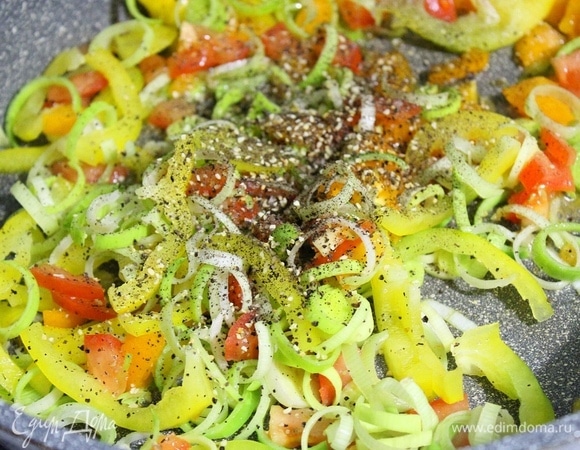 Кальмары чистим под горячей водой (не варить!). Креветки залить кипятком, дать им недолго постоять и очистить. На сковороду вливаем оливковое масло. Лук-порей мелко нарезаем, помидор — кубиками, перец — соломкой. Отправляем все в сковороду, посыпаем солью и перцем. В кастрюлю вливаем стакан воды и добавляем половину стакана булгура, варим под закрытой крышкой 15 минут.