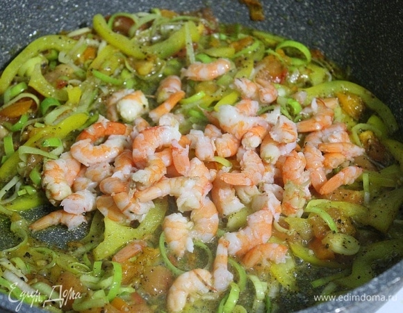 Креветки разрезаем на 2–3 части и помещаем в сковороду, перемешиваем и жарим 5 минут. Затем добавляем булгур, перемешиваем и жарим 5 минут.